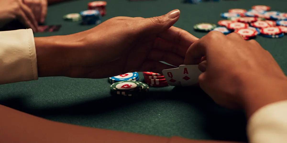 Ein Pokerspieler mit As-Dame suited auf der Hand plant seinen nächsten strategischen Zug.